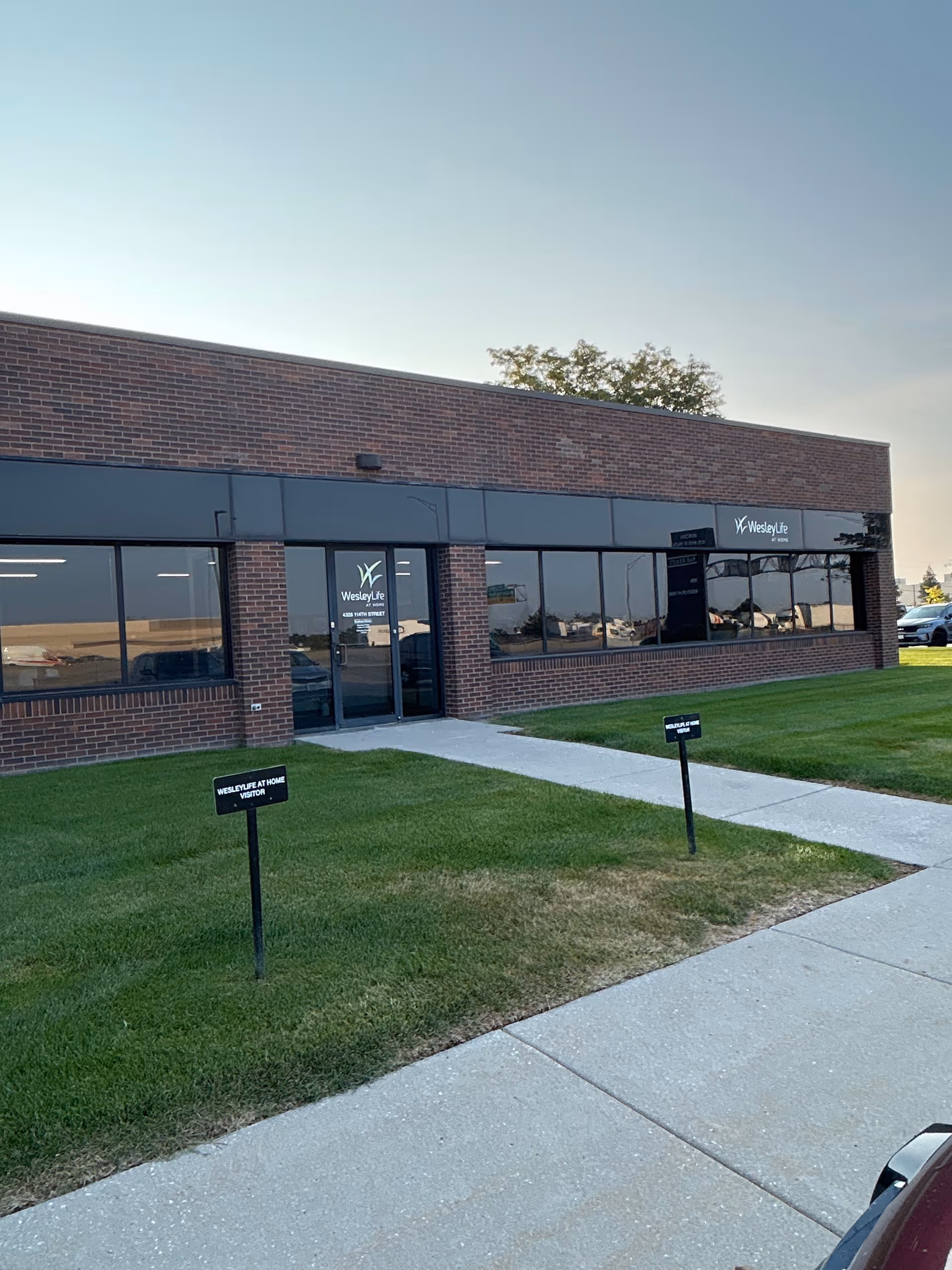 Brick building with large windows, glass door, and WesleyLife signage outside.