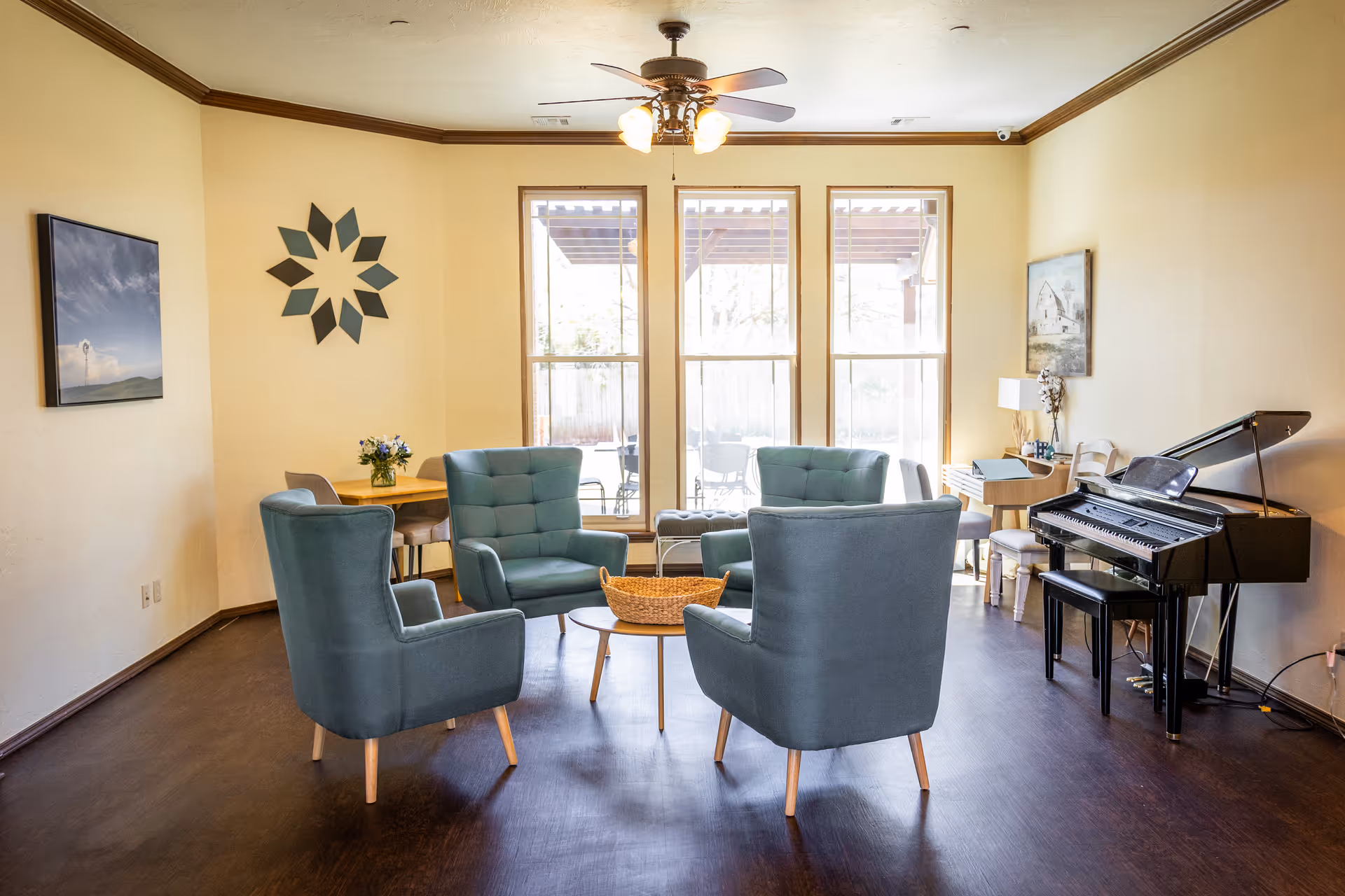 Legacy Senior Living lounge with teal chairs, piano, and large windows.