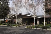 Front view of Claremont Care Center, a single-story stone building with driveway and landscaping.