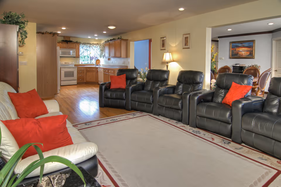 Cozy common living room with leather recliners and a kitchen in the background.