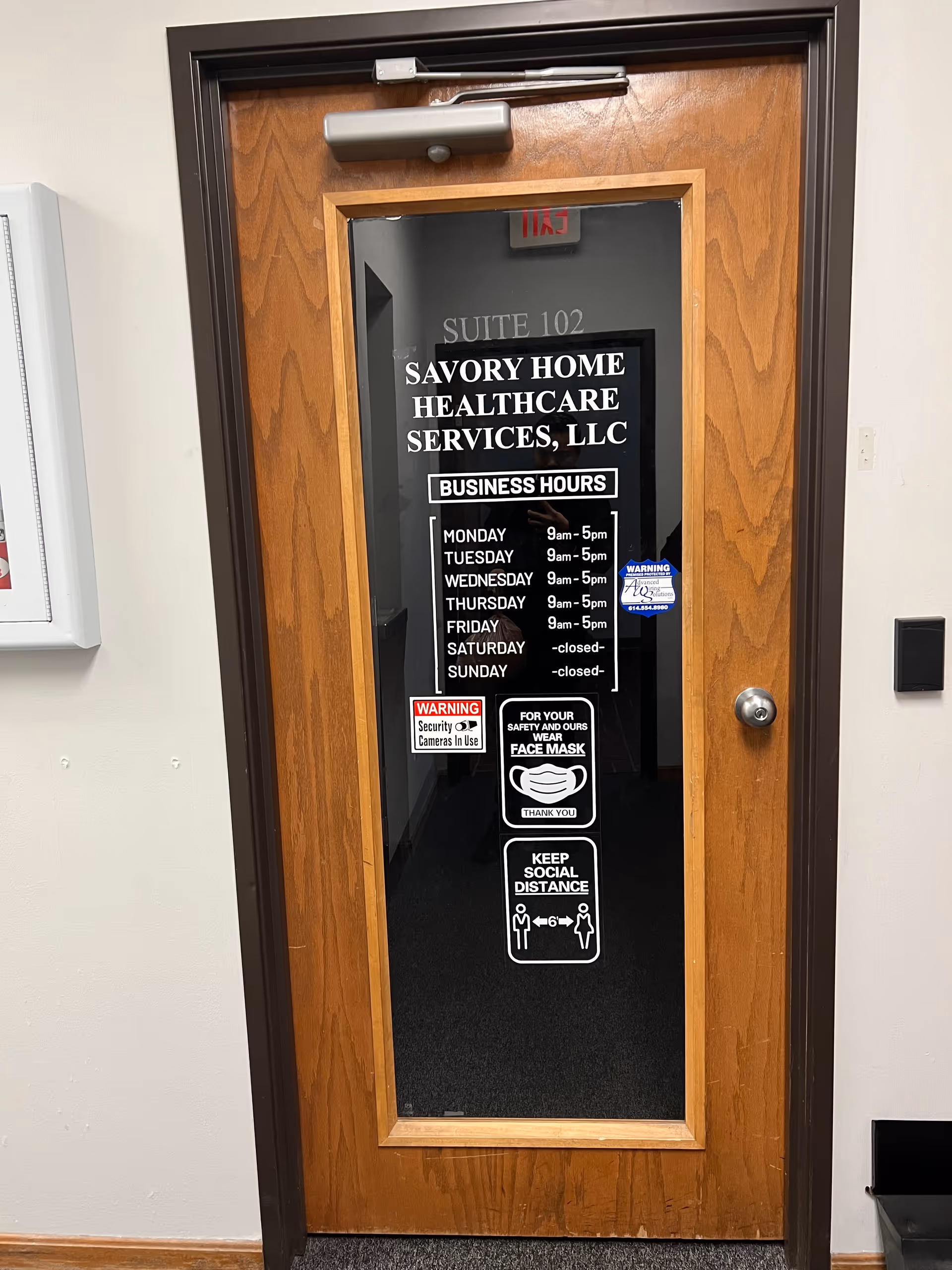 Wood-framed interior door displaying Savory Home Healthcare Services, LLC signage and business hours.