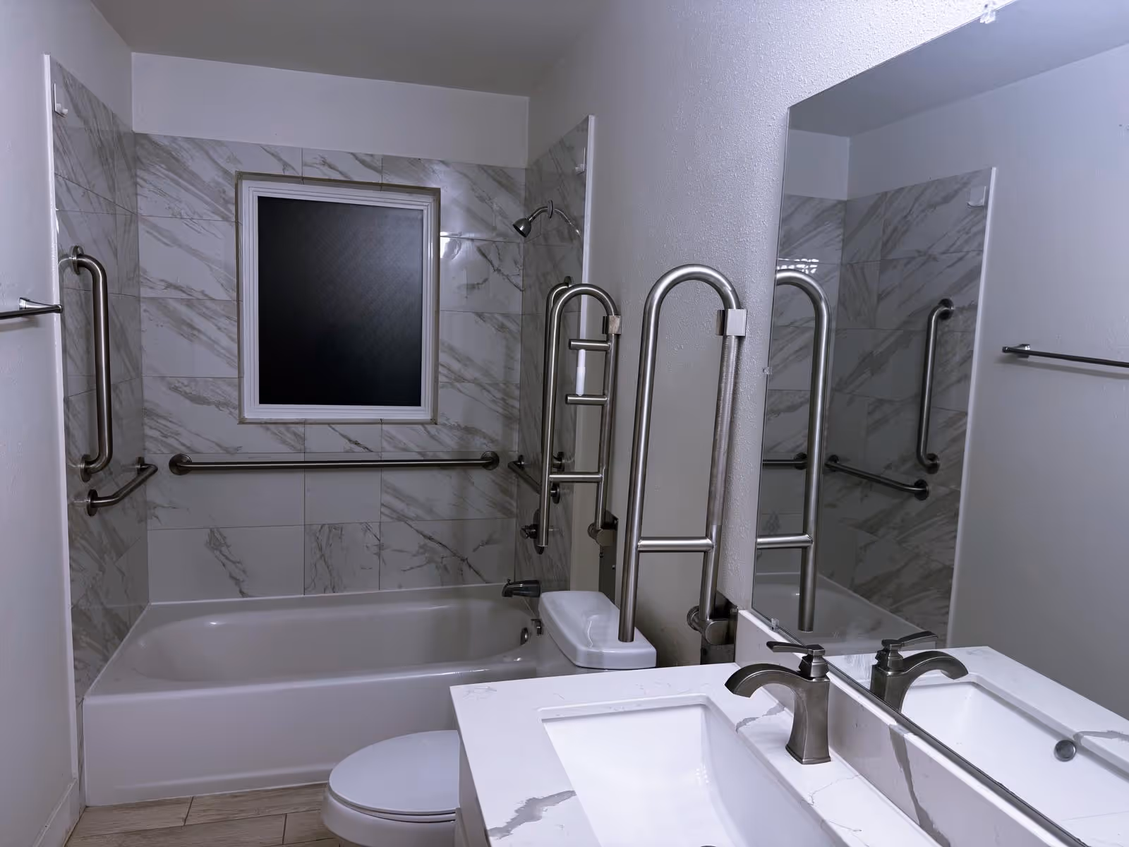 Accessible bathroom with bathtub, wall grab bars, and a sink.