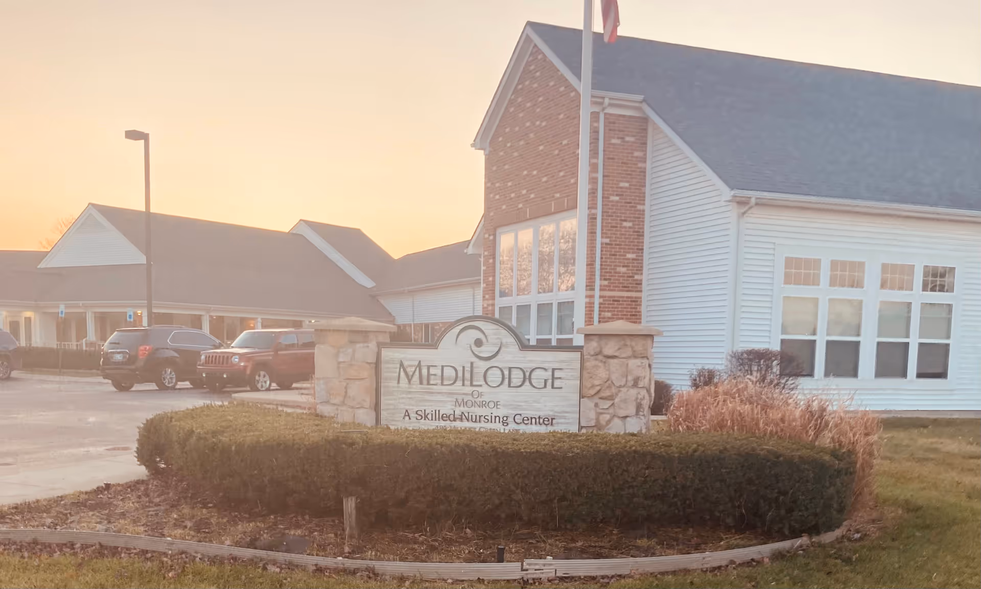 Exterior view of Medilodge of Monroe with front sign and parking.