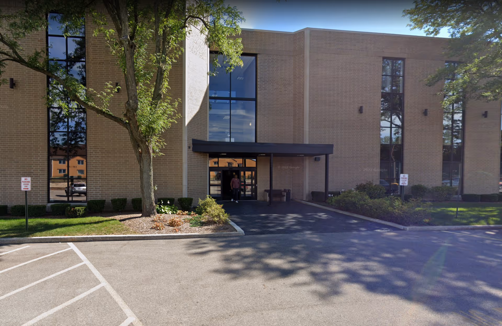 Exterior view of a brick senior living facility with a covered entrance and parking.