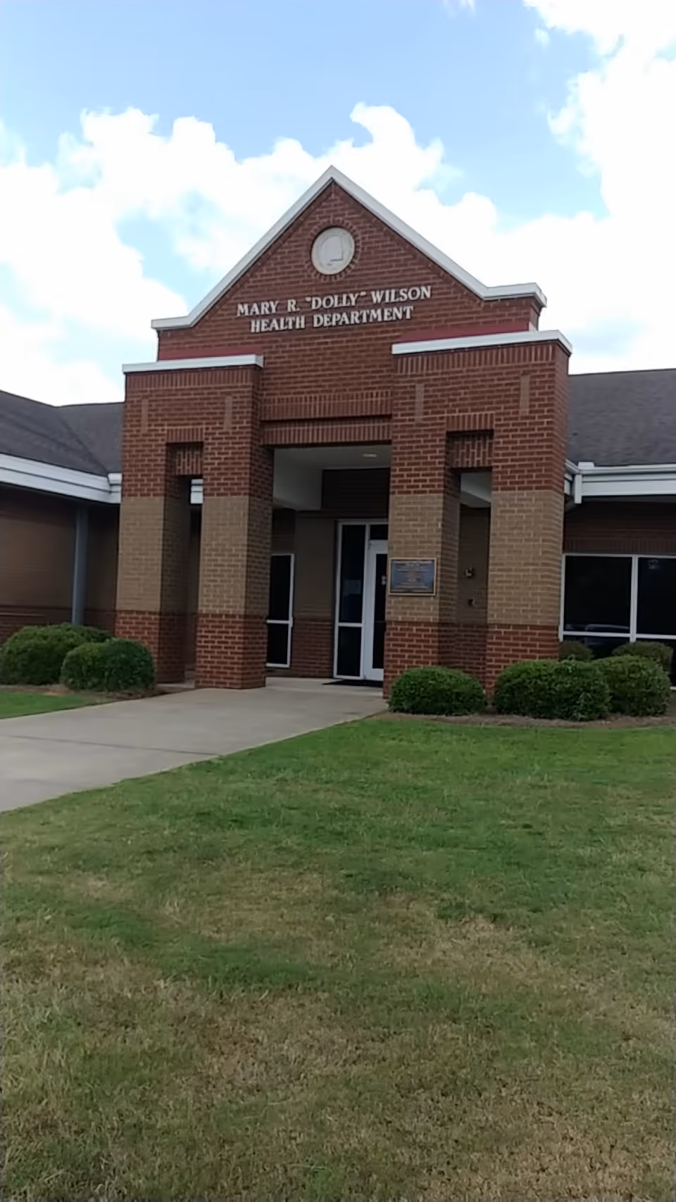 Brick Mary R. Dolly Wilson Health Department building with a covered entrance and green lawn.