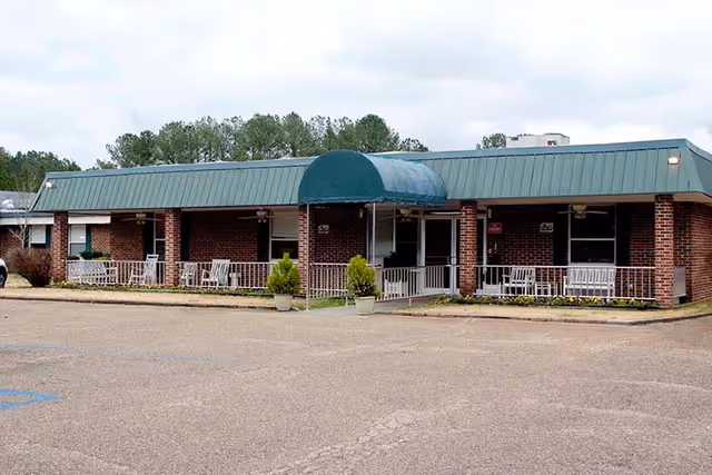 Facade of Hendrix Health and Rehabilitation with brick walls, green awning, and outdoor seating.