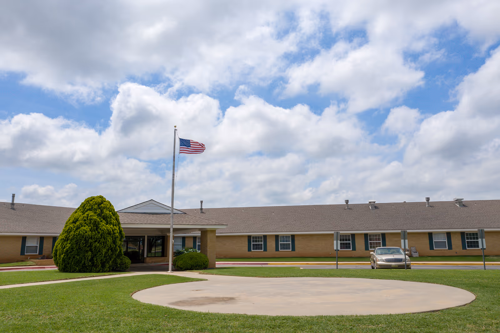 Exterior view of a single-story brick assisted living facility with a circular driveway.