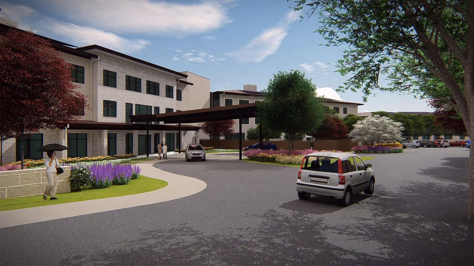 Exterior view of The Reserve at Lake Austin senior living facility showing a three-story building with large windows, a covered entrance driveway, landscaped gardens with trees and flowers, several parked cars, and a person walking with an umbrella on the sidewalk.