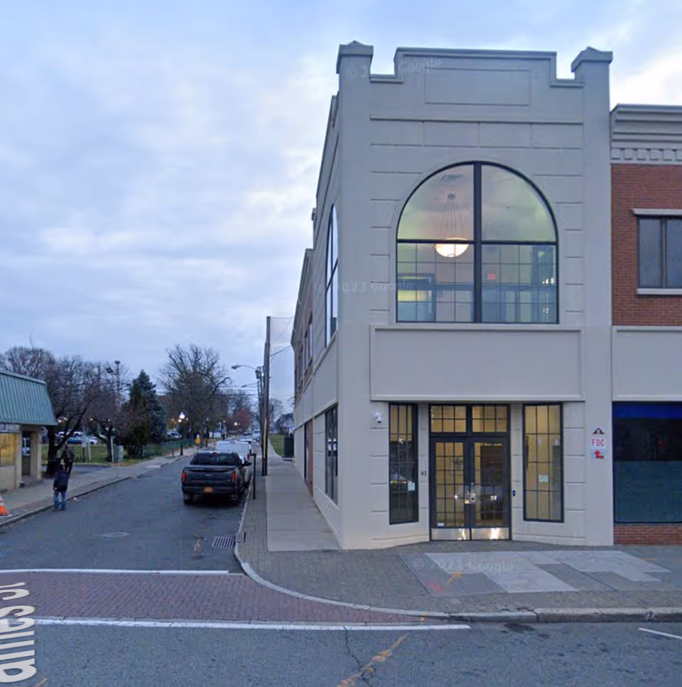 Modern storefront-style senior living building with arched window and glass entrance.