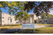 Exterior view of Highland Rehabilitation & Nursing Center with sign and trees.