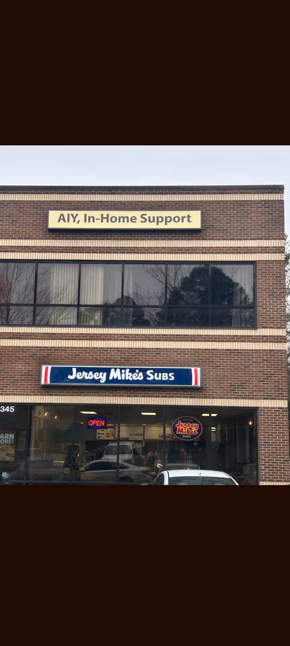 Brick storefront with 'Along In-Home Support' sign above Jersey Mike's Subs.