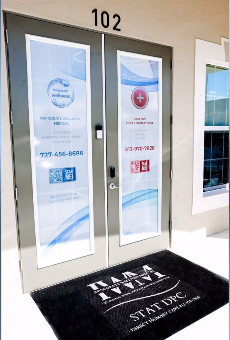 Two glass doors with Invigorate Wellness Medical branding, 102, and a black mat outside.