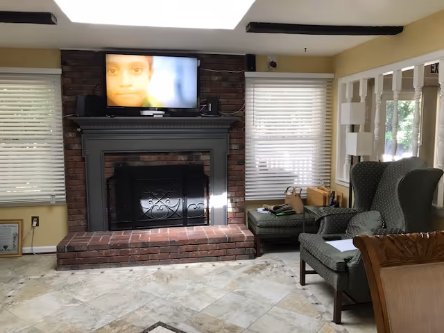 Living room at Green Pasture Residences with a brick fireplace and TV.