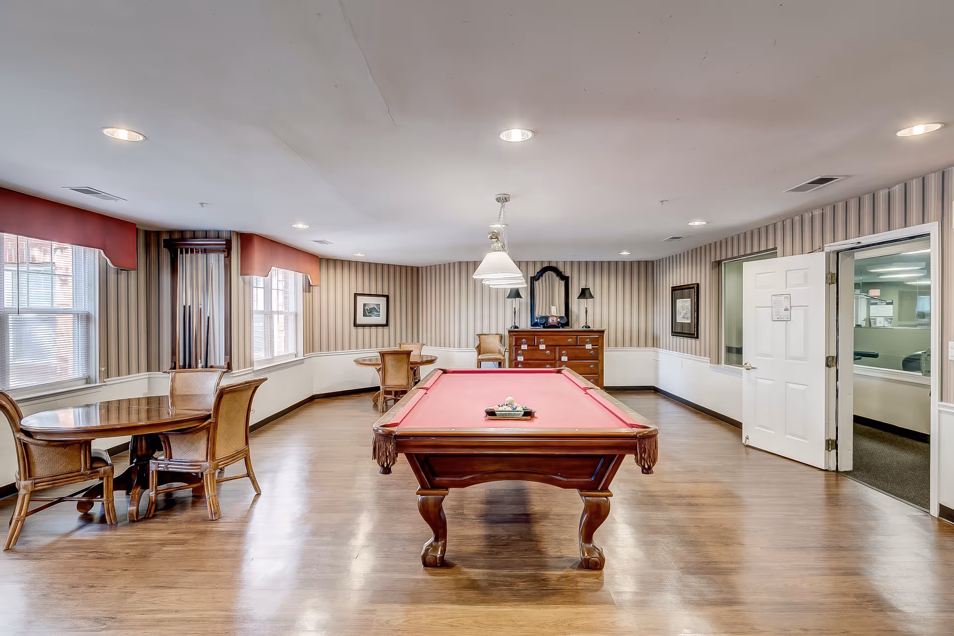 Spacious indoor recreation room with a red pool table and round tables.
