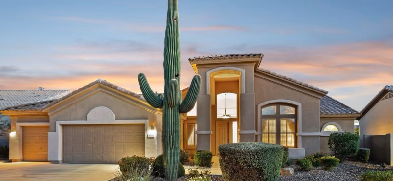 Front view of Holy Family Assisted Living's desert-style exterior with a tall cactus.