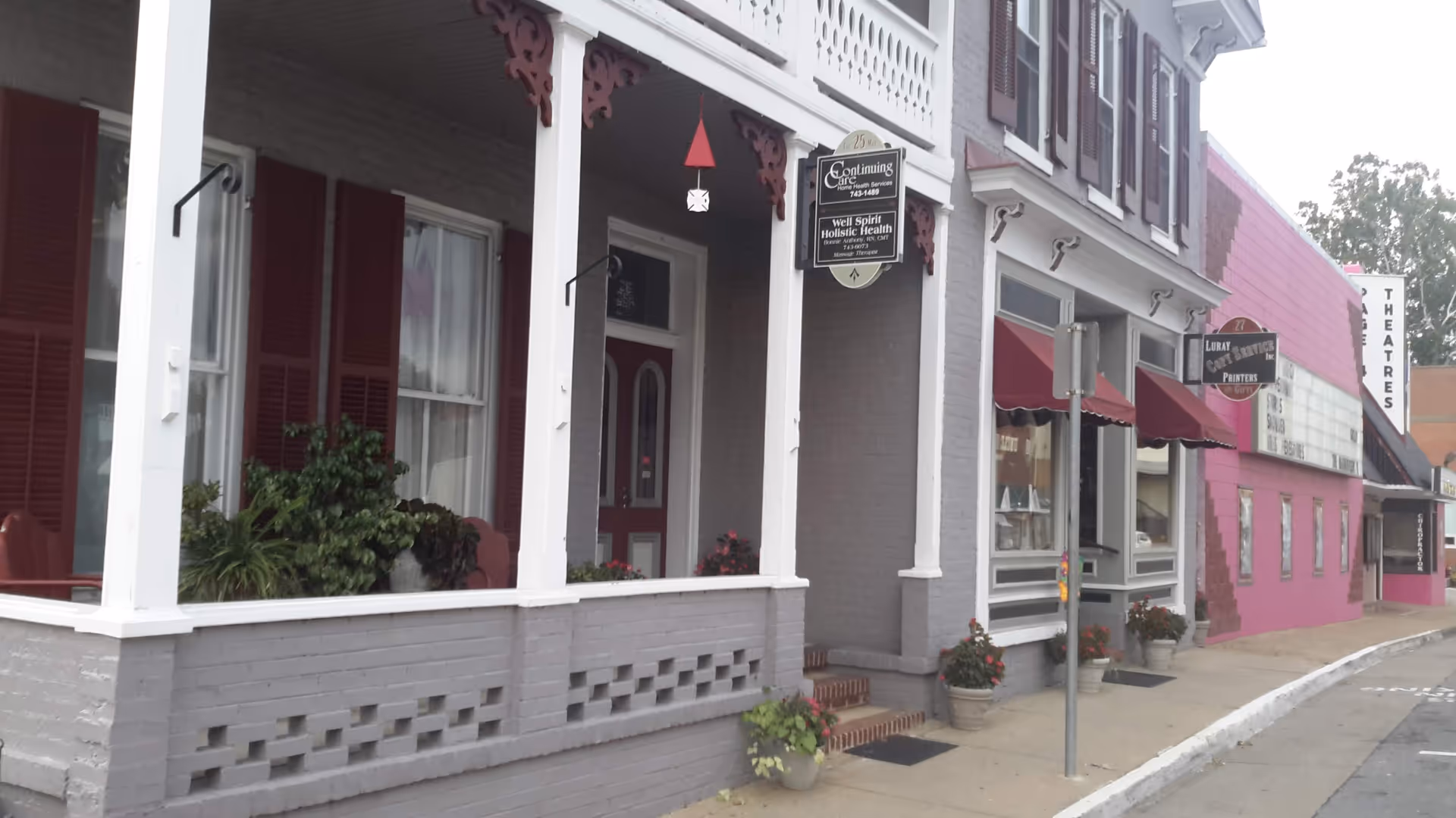 Exterior storefront of a senior living facility with porch, planters, and signage.
