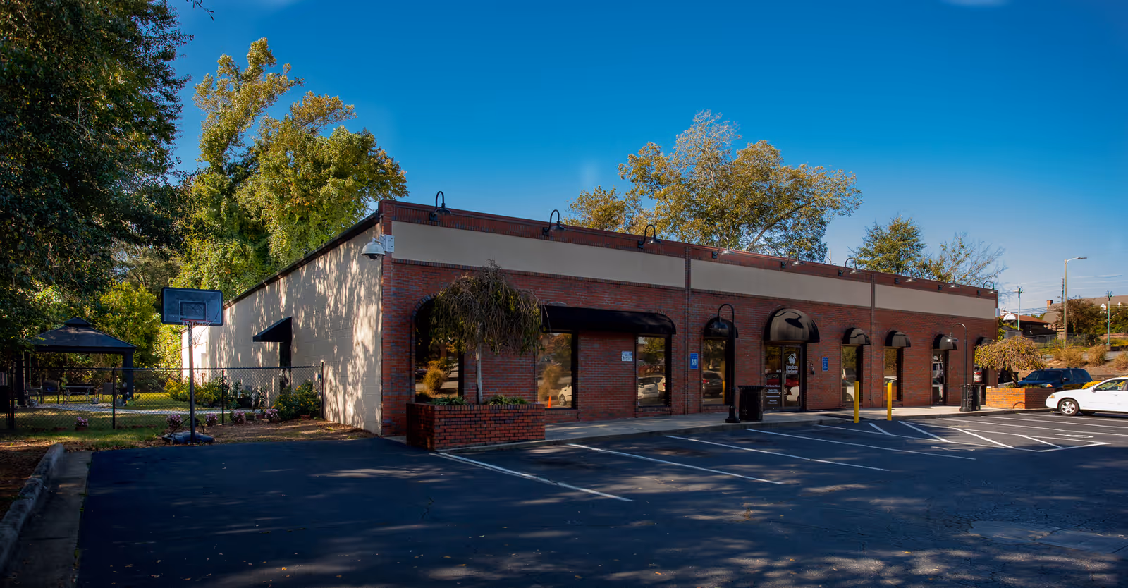 Front exterior of a brick building with arched windows and a parking lot.
