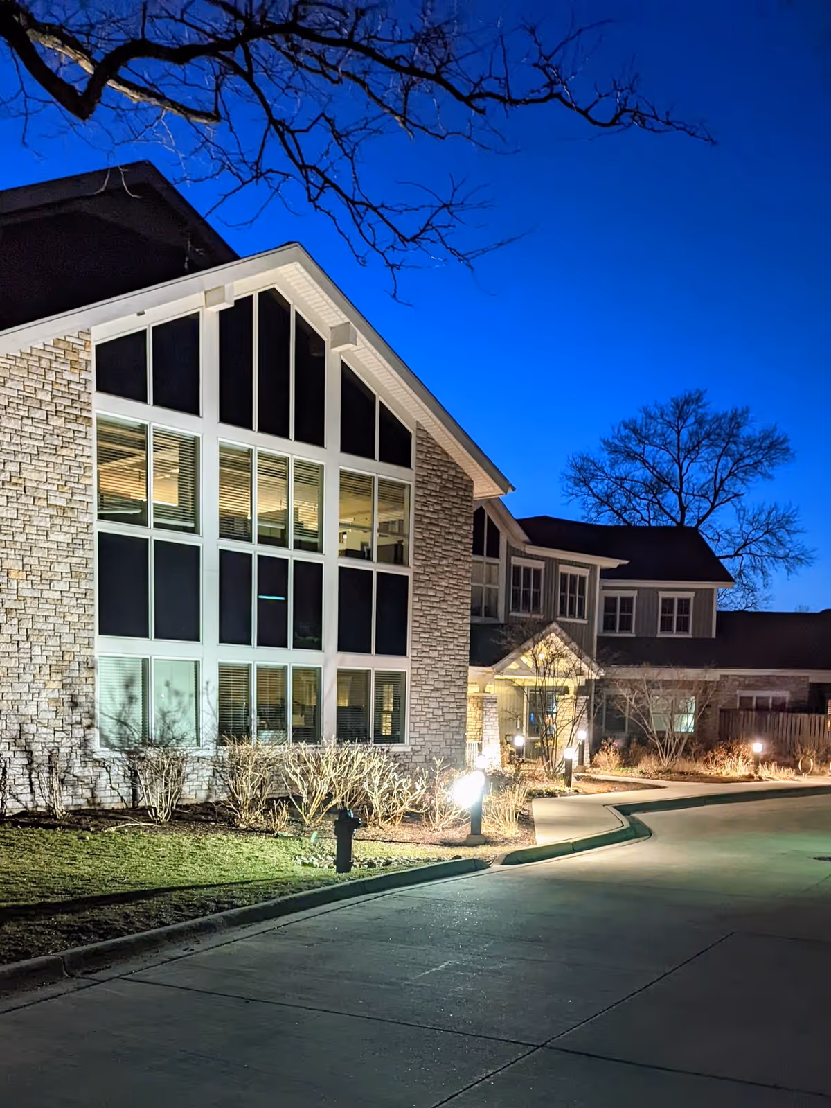 Nighttime exterior of a JourneyCare Hospice building with large glass windows and lit walkway.