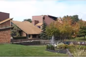 Exterior view of Williamstowne Senior Apartments with a pond, landscaping, and trees.