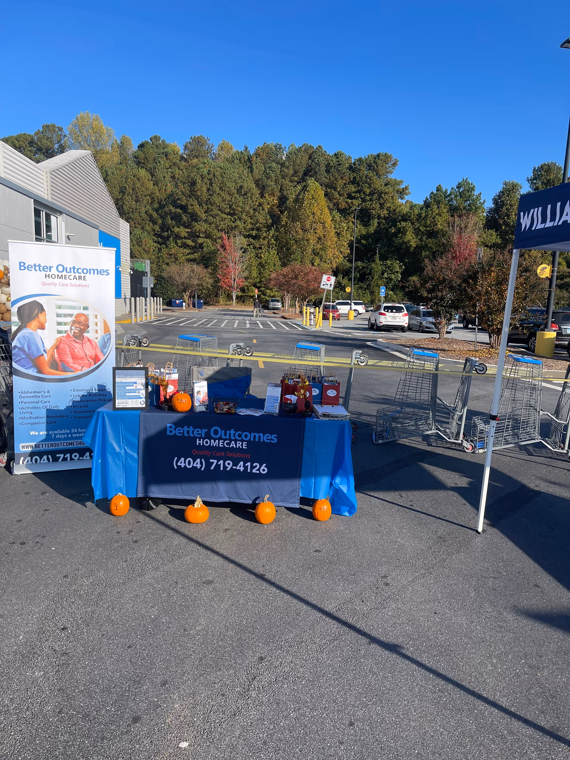 Outdoor promotional booth for Better Outcomes Home Care in a parking lot with pumpkins.