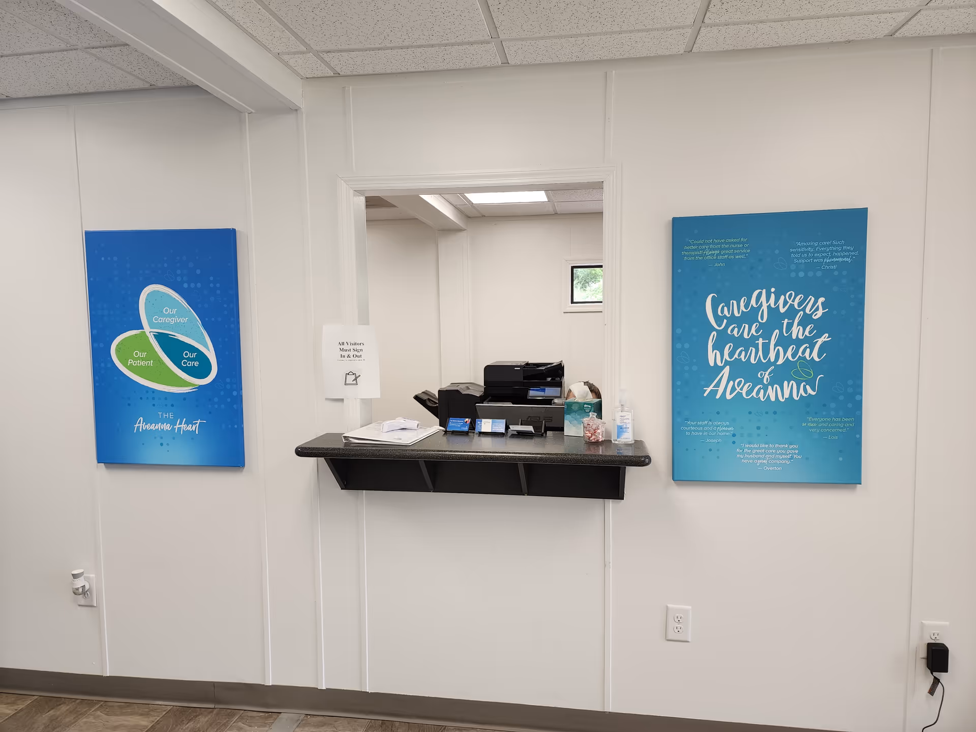 Interior reception area featuring a counter, printer, papers, sanitizer, and blue posters.