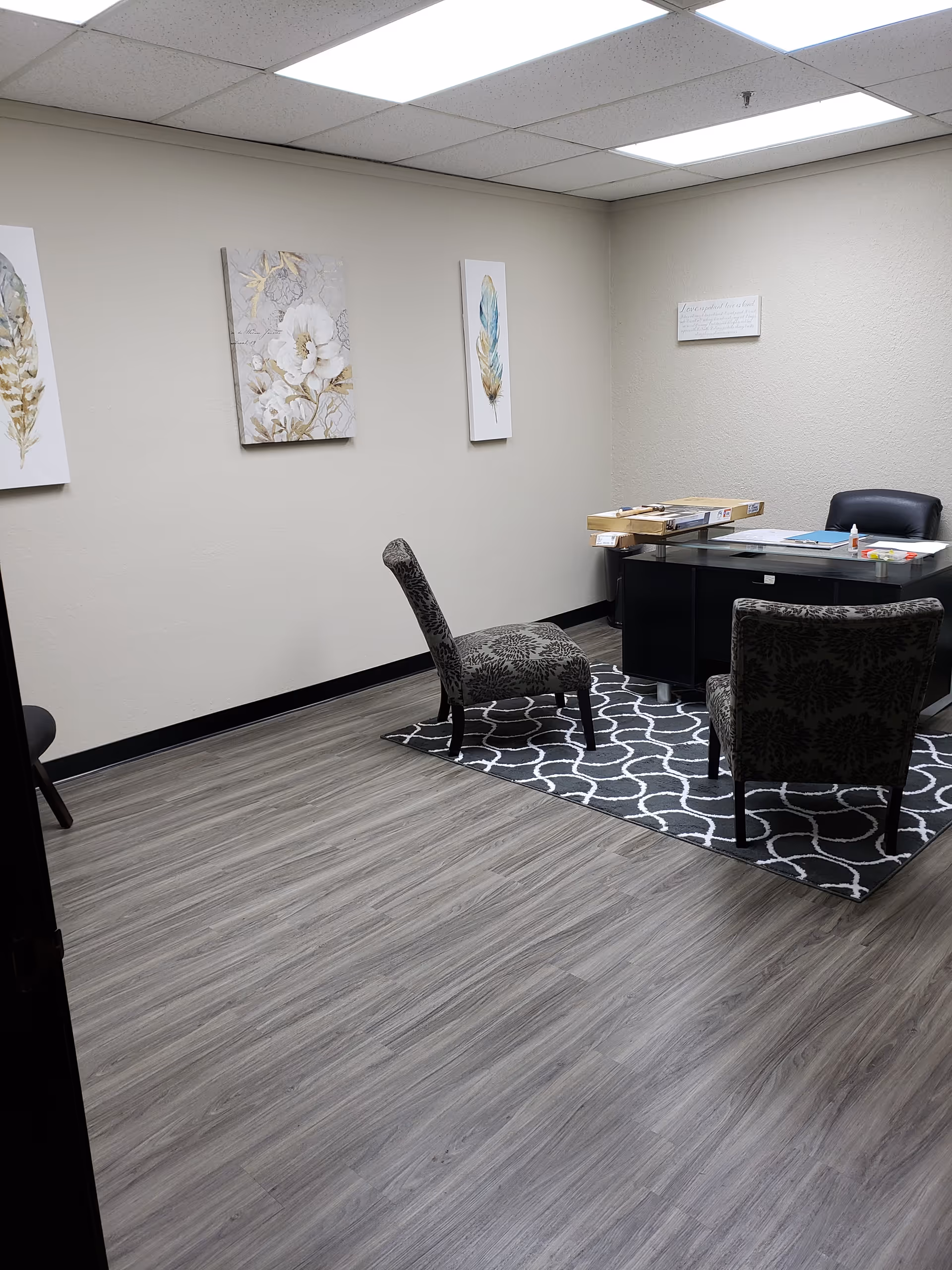 A small office in a senior facility with a desk, chairs, and wall art.