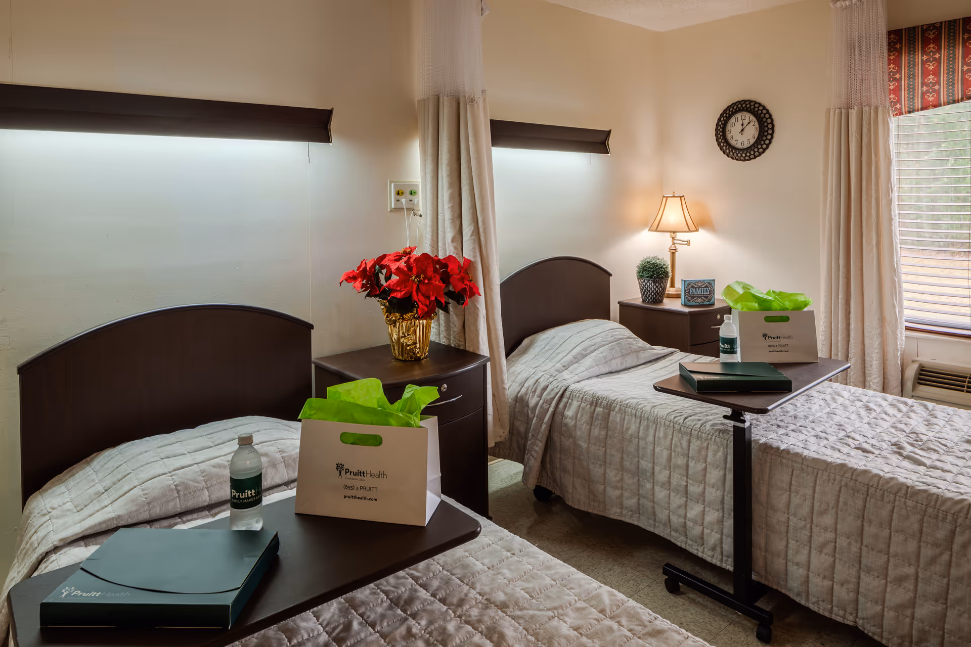 Two twin beds with matching quilted covers flank nightstands in a bright shared patient room.