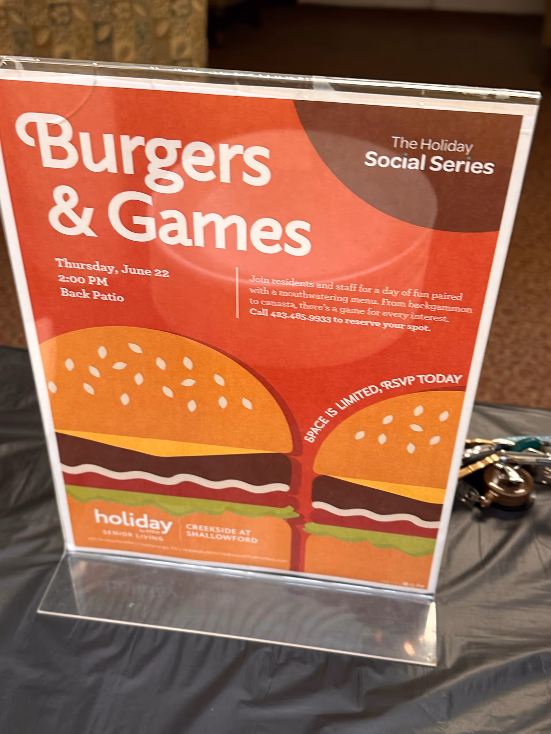 Colorful promotional poster for Burgers and Games on a table inside a senior living facility.