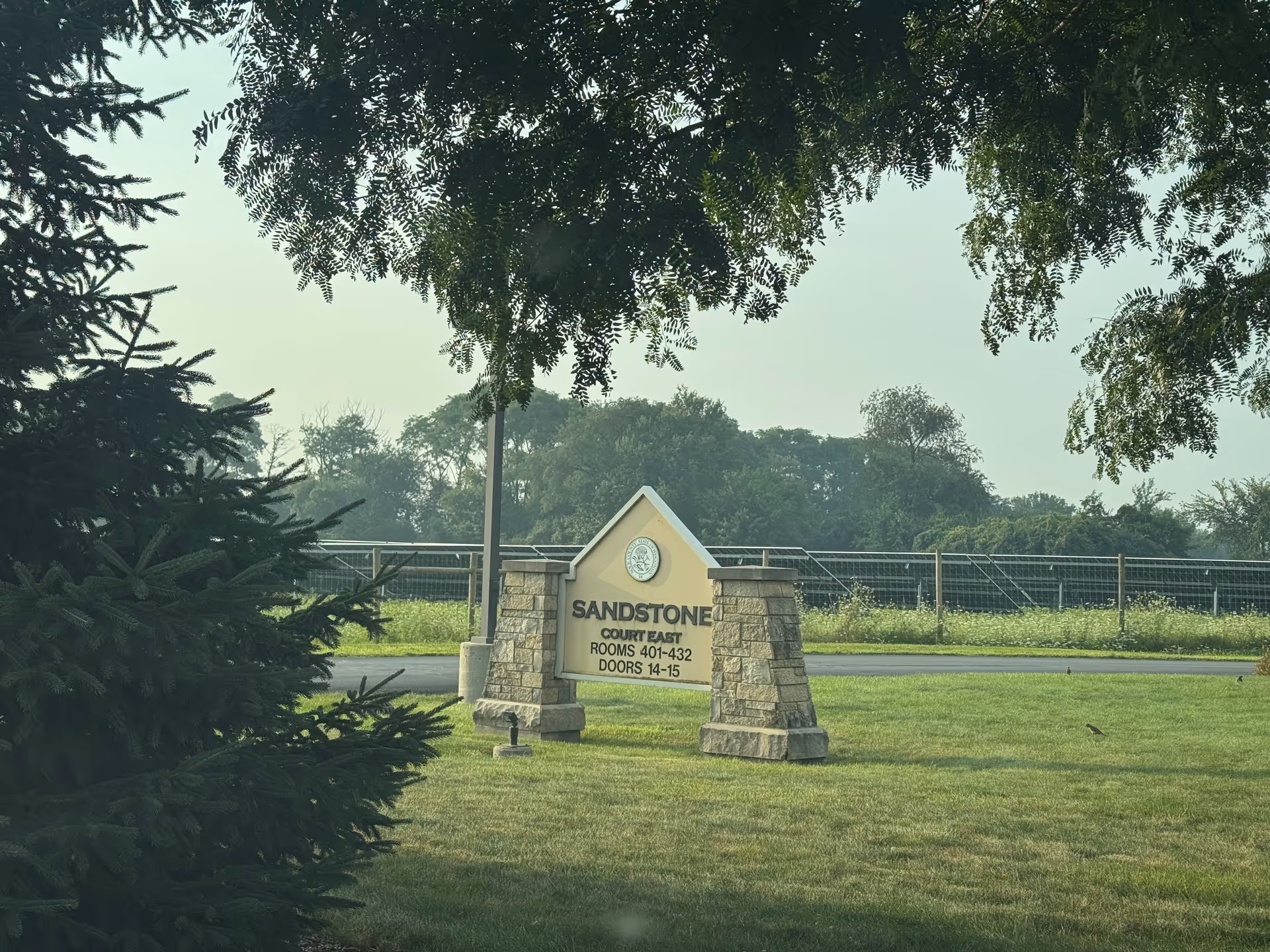 Stone sign entrance reading Sandstone Court East on a grassy lawn with trees.