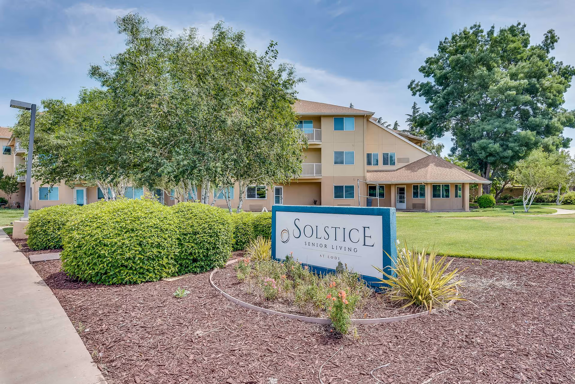 Exterior view of Solstice Senior Living at Lodi showing the building, landscaped grounds, and a prominent Solstice sign.