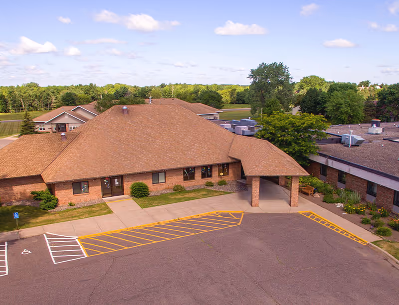 A brick senior living facility with a covered entrance and surrounding parking lot.