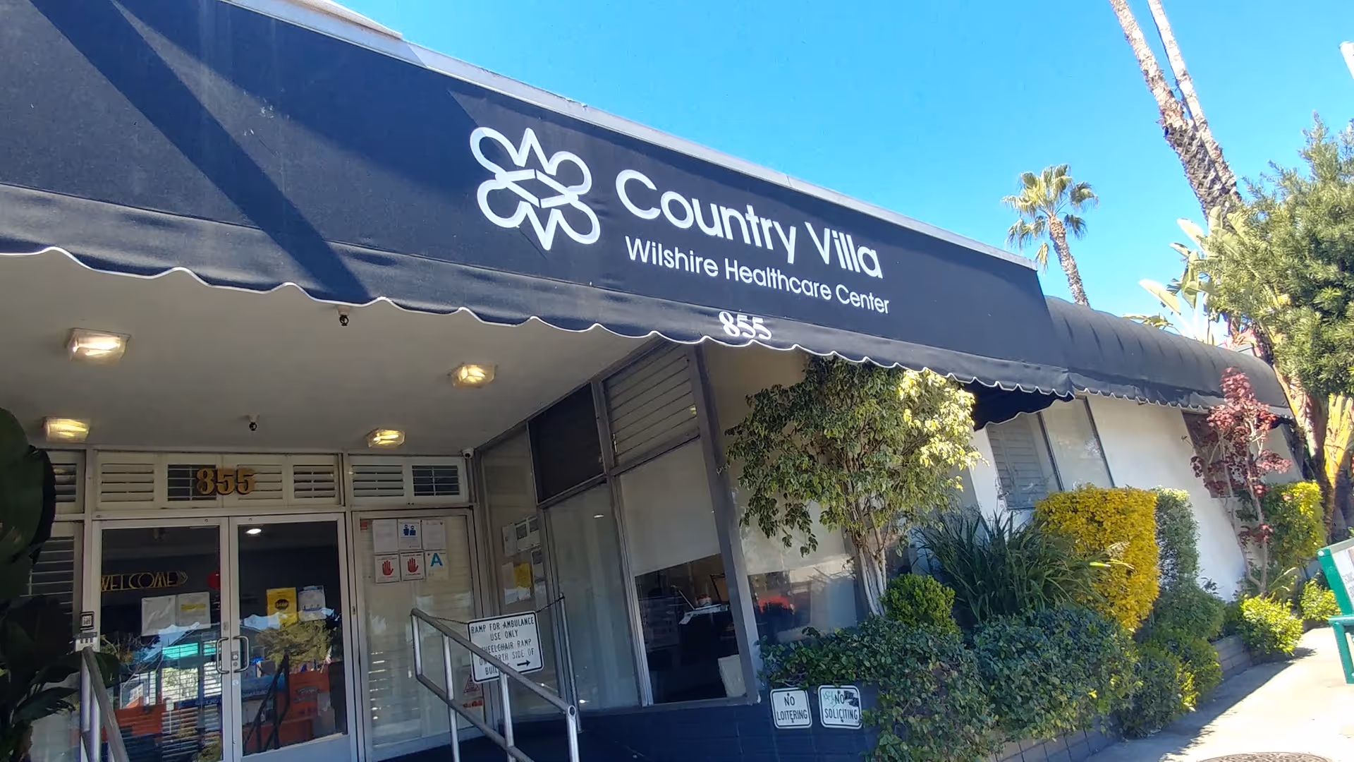 Exterior view of a storefront building with a navy awning labeled Country Villa Wilshire Healthcare Center.