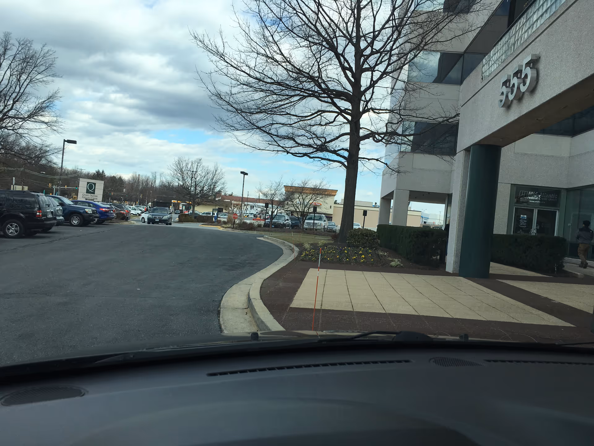 View of building exterior with parking lot and bare trees outside a senior living facility.