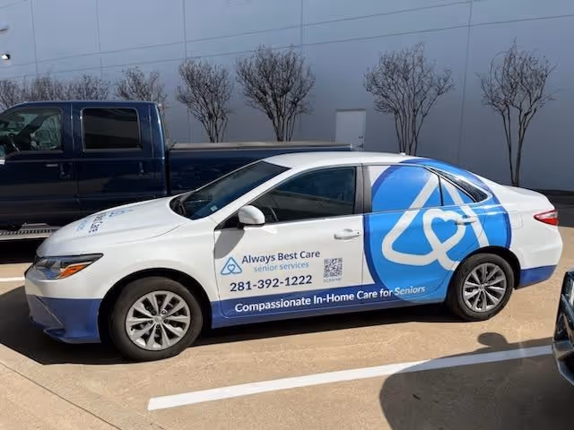Branded sedan parked in a lot features Always Best Care signage for in-home senior care.