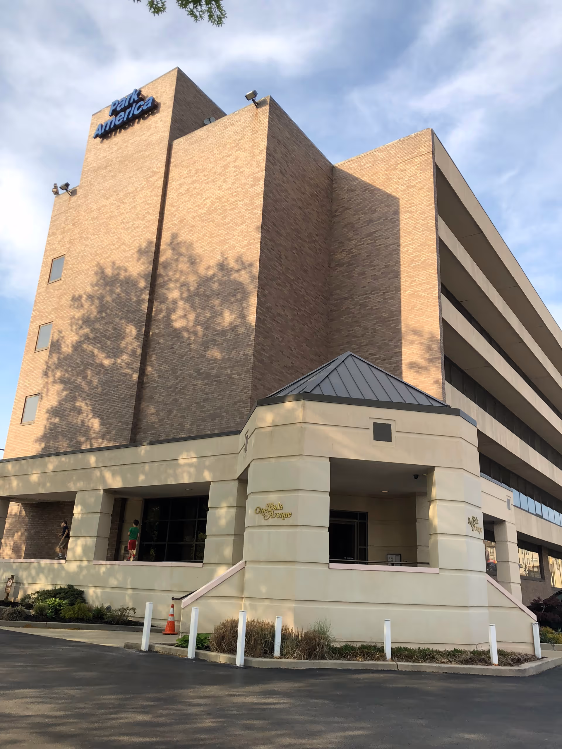 Tall brick senior living building exterior with beige entrance and parking area.