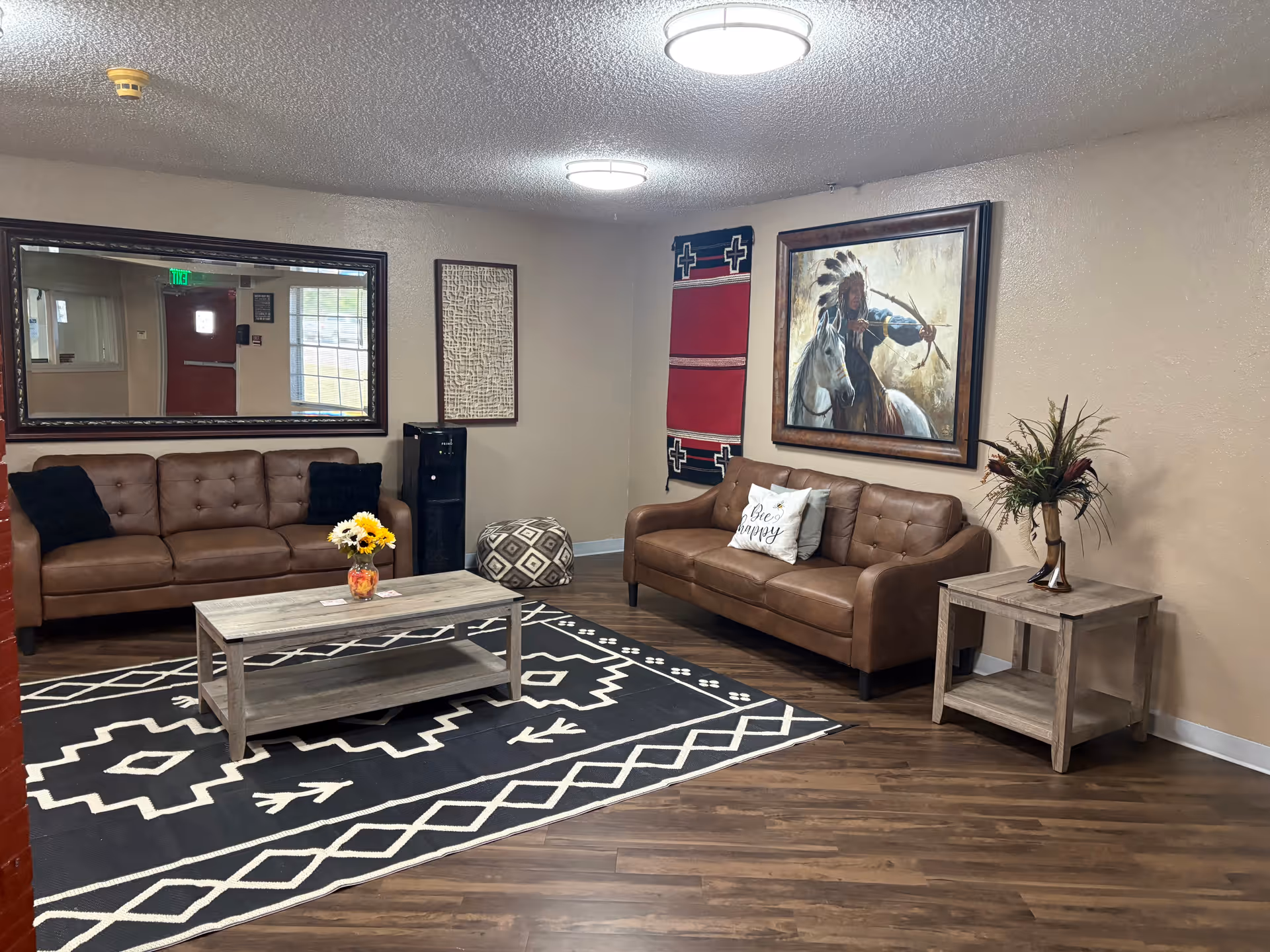 A lounge area with two tan sofas, coffee table, rug, wall art, and side table.