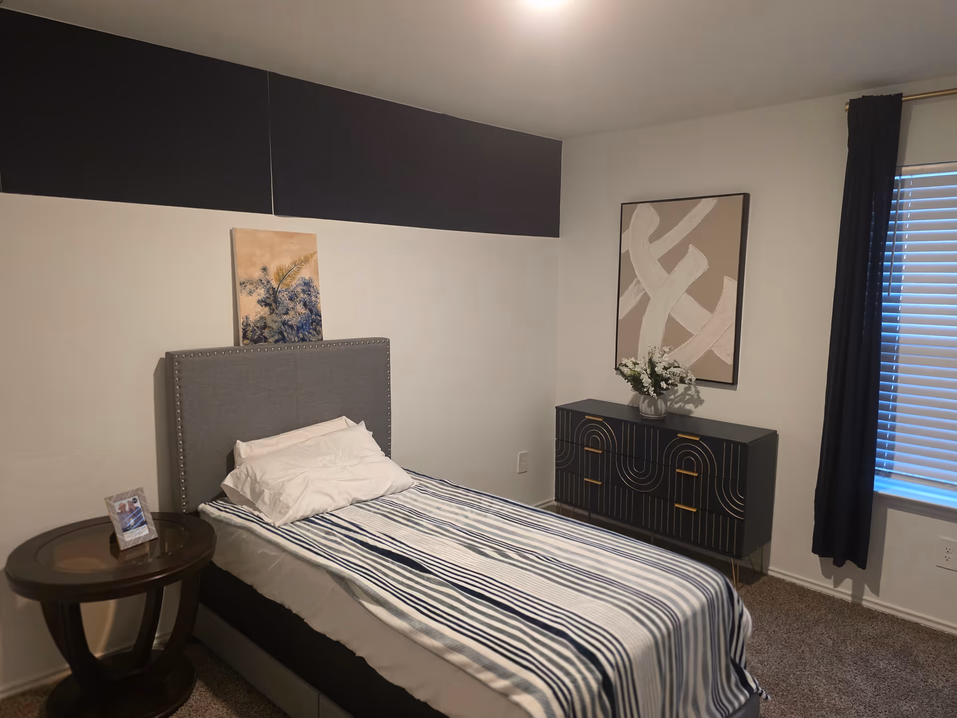 Bedroom at Golden Pheasant Chalet senior living facility with striped bed and dresser.