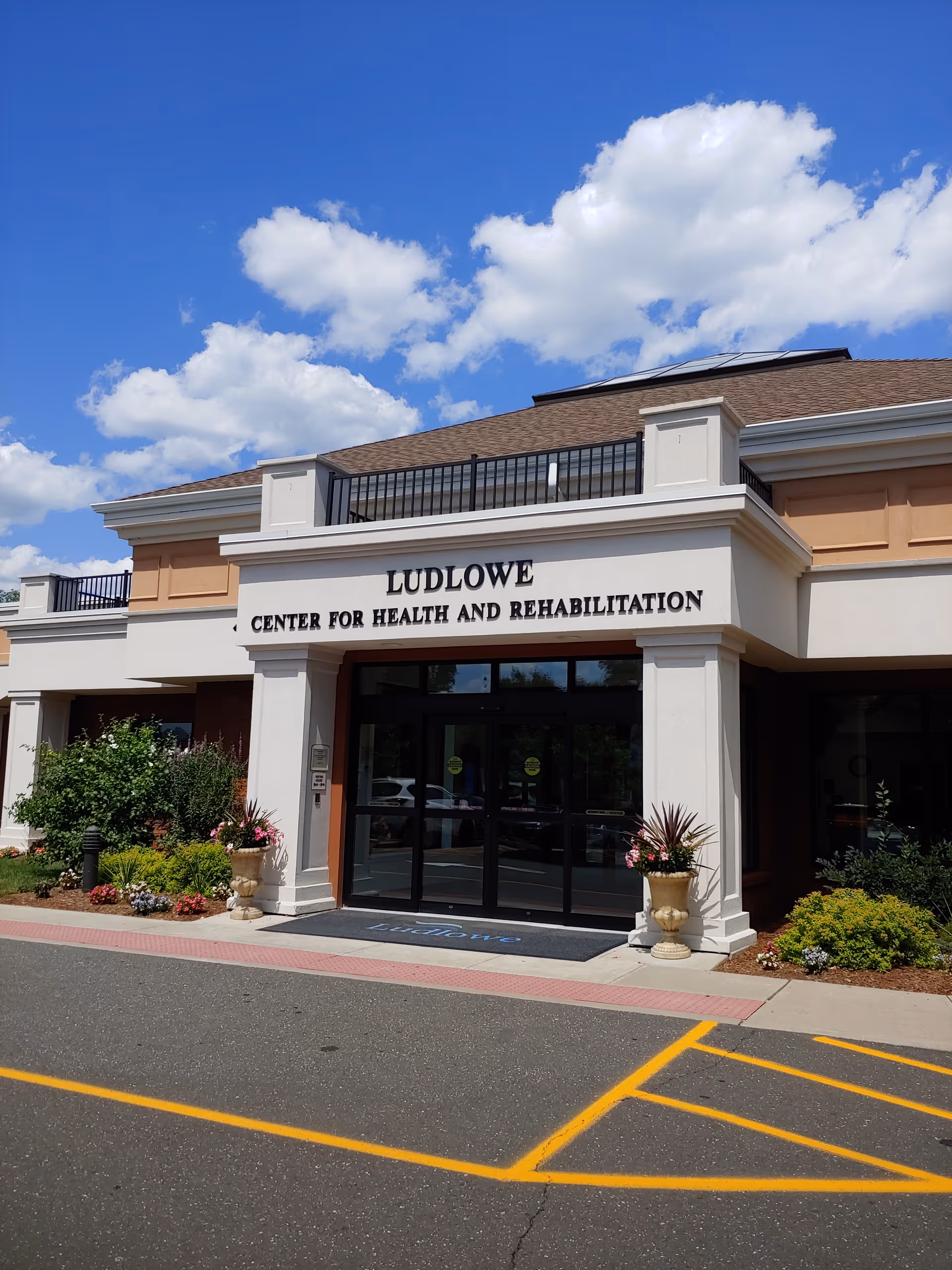 Front entrance of Ludlowe Center for Health and Rehabilitation under a blue sky.