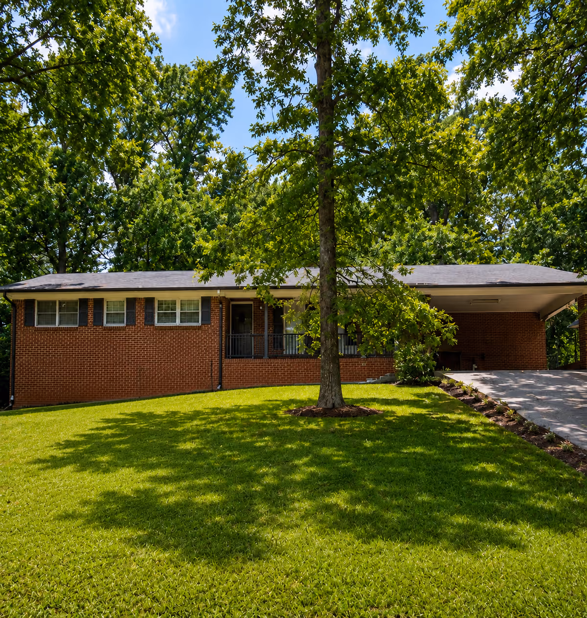 Front exterior of a single-story brick senior living facility with a manicured lawn and trees.