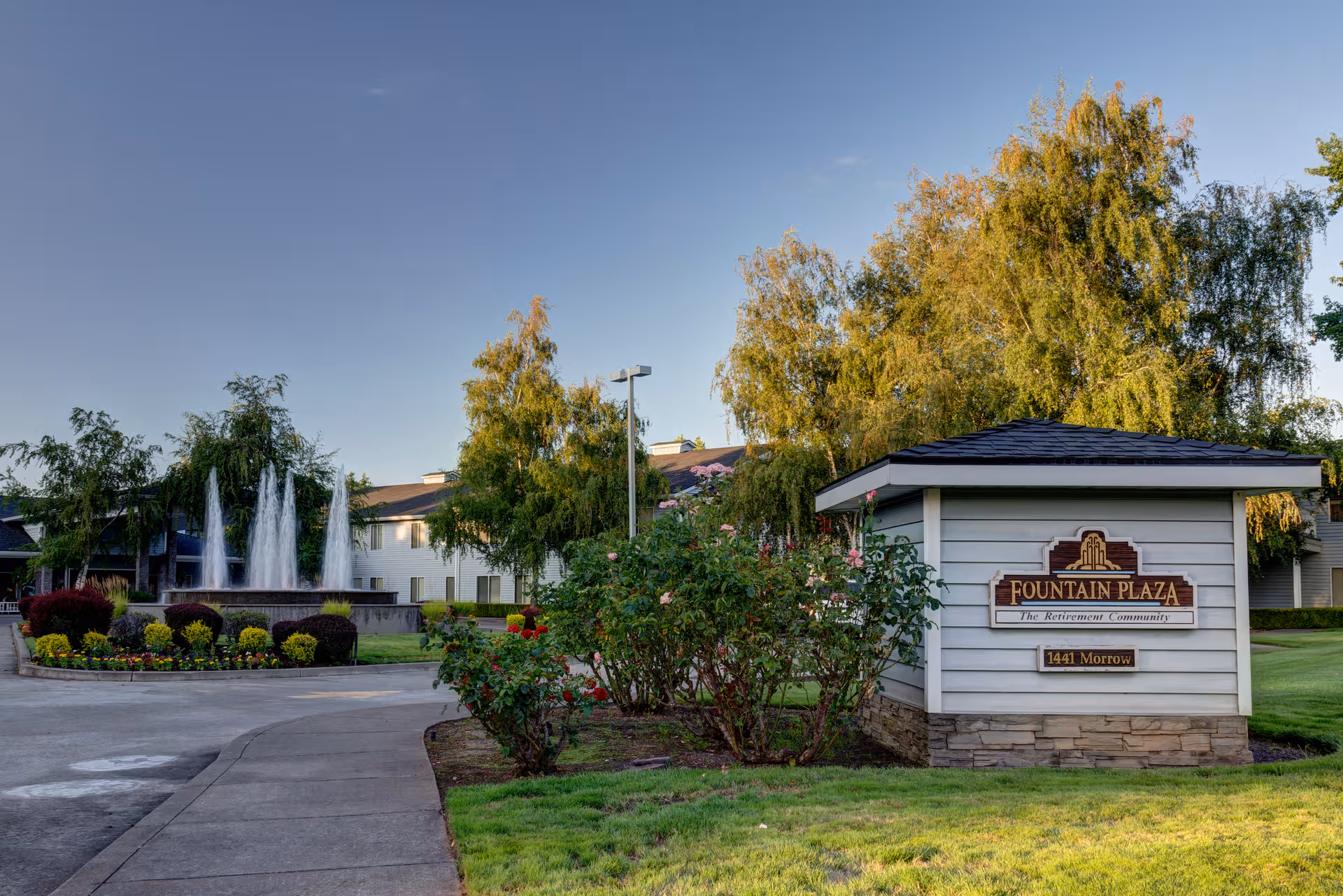 Front view of Fountain Plaza retirement community sign, fountain, and landscaped grounds.