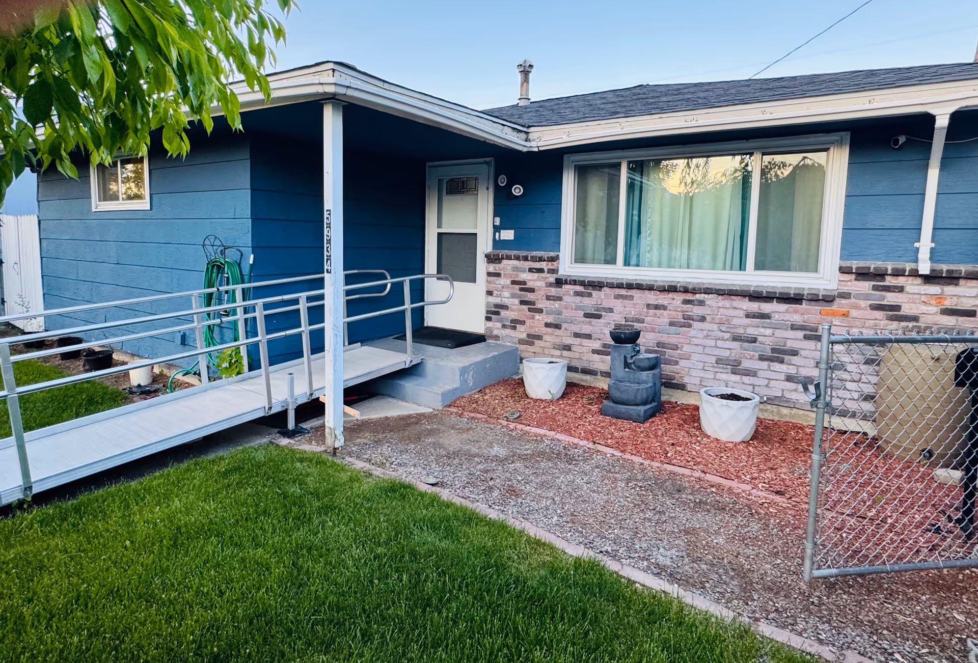 Exterior view of Caringrove Adult Family Home with blue siding, ramp, and fenced yard.