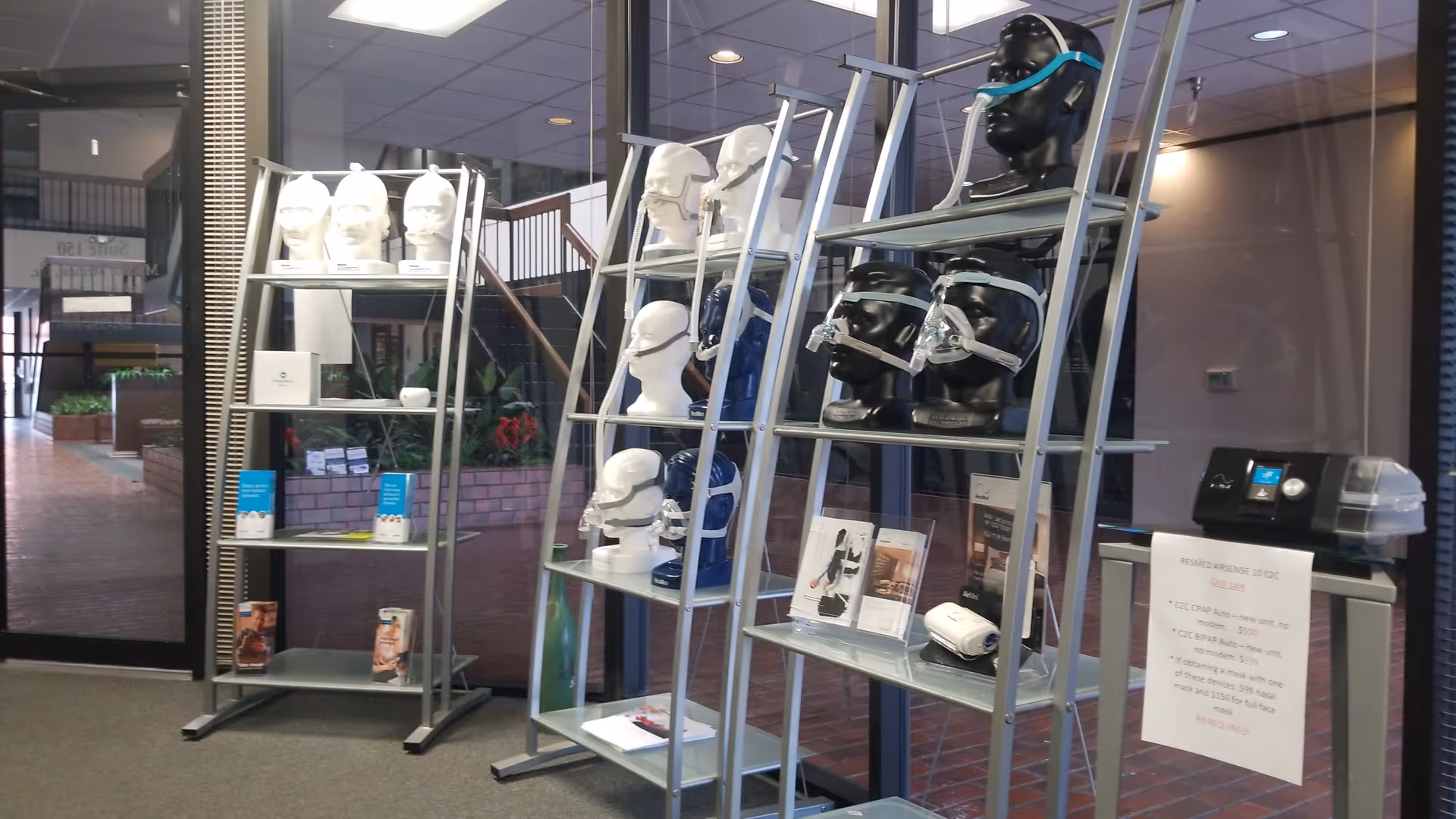 Interior showroom displaying CPAP masks and medical equipment on metal shelves with mannequin heads.