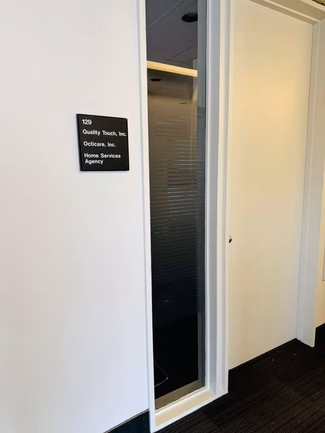 White hallway with frosted glass door and wall sign for Quality Touch, Inc.