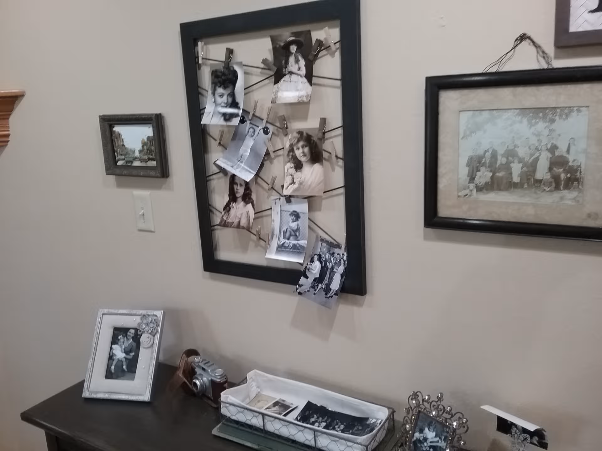 Interior wall with framed photos and a table displaying picture frames.