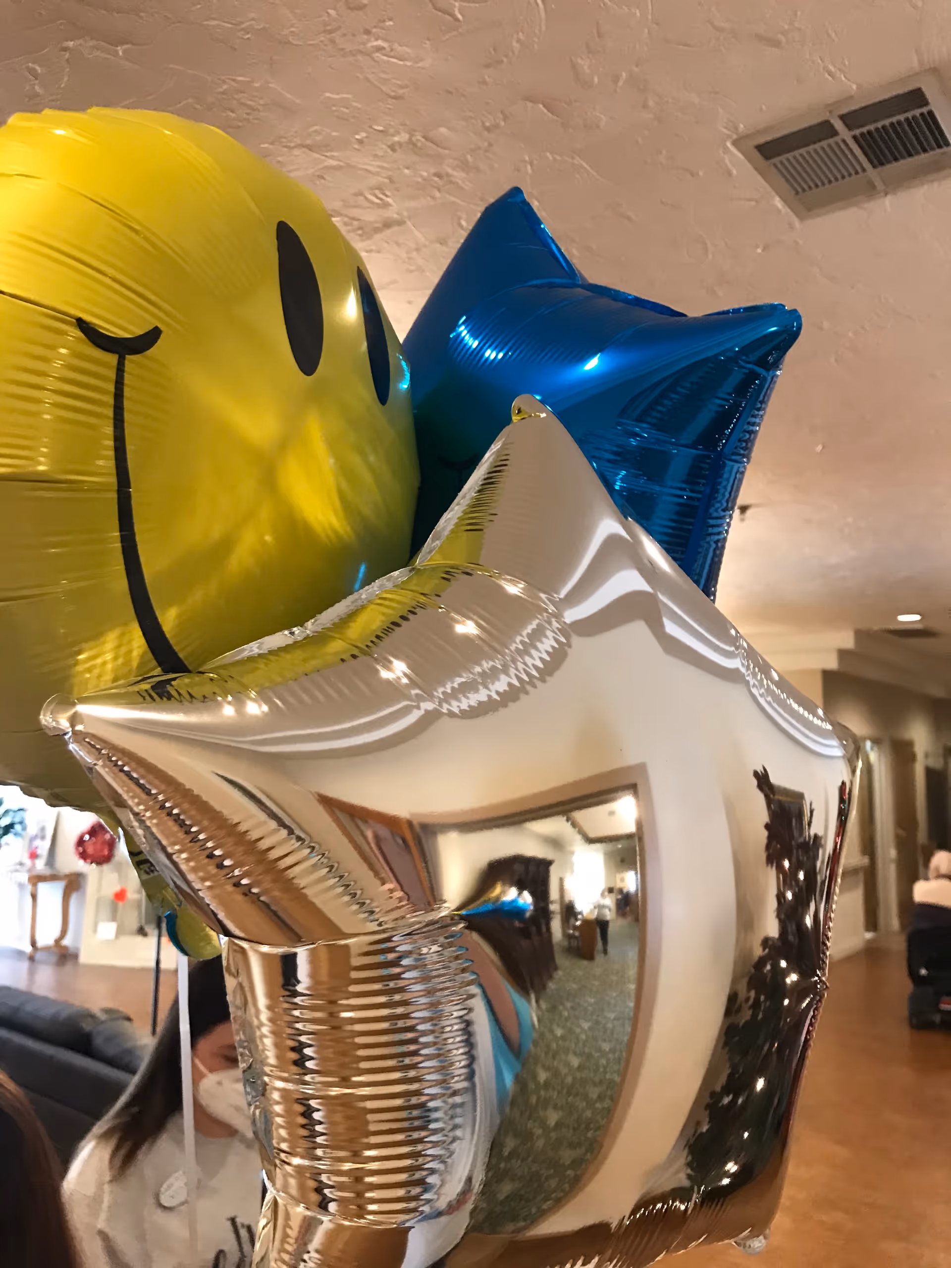 Colorful balloons, including a silver star, decorate a senior living lobby interior.