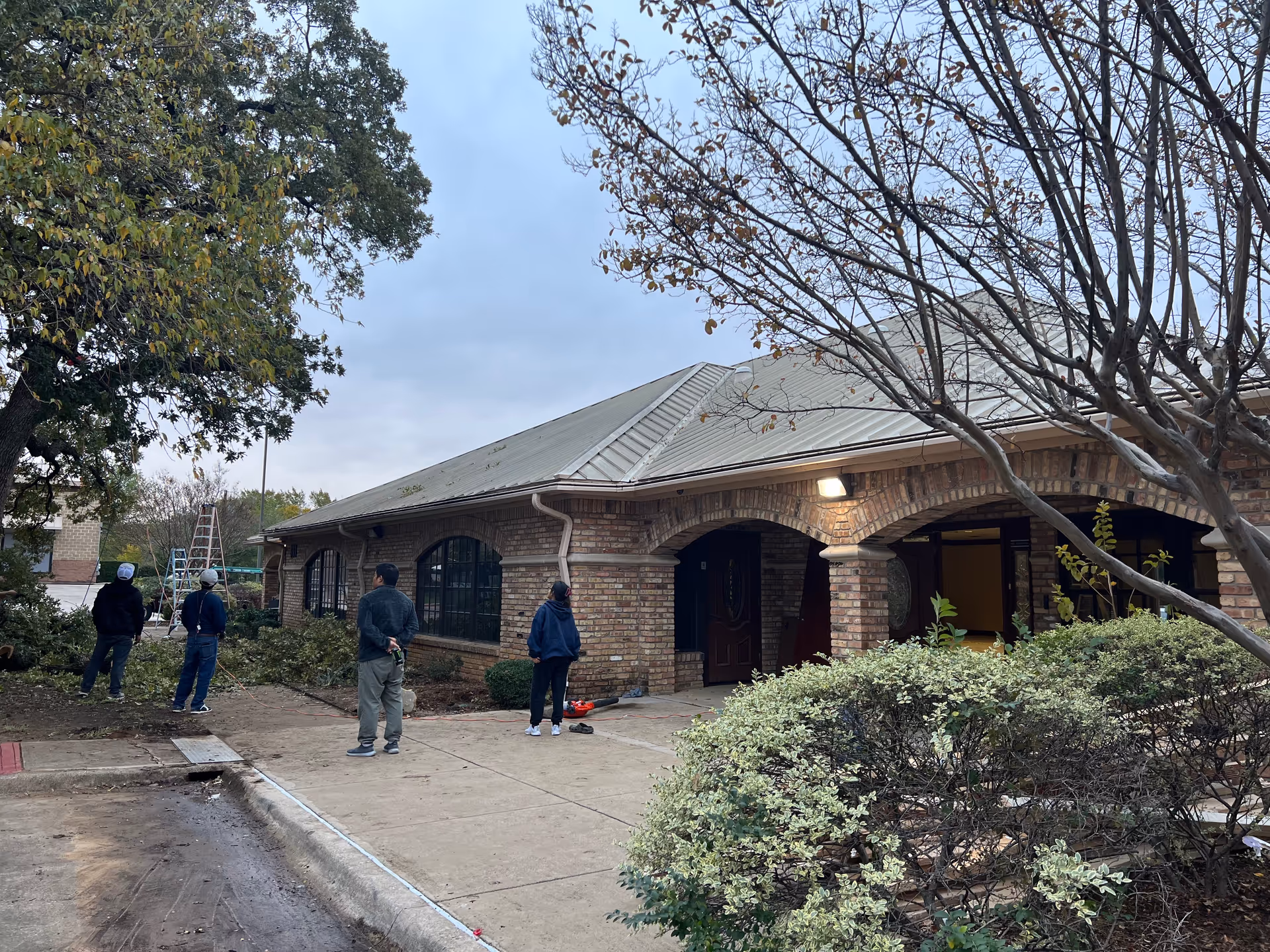 Brick facility exterior with arched windows, front entrance, and workers outside.