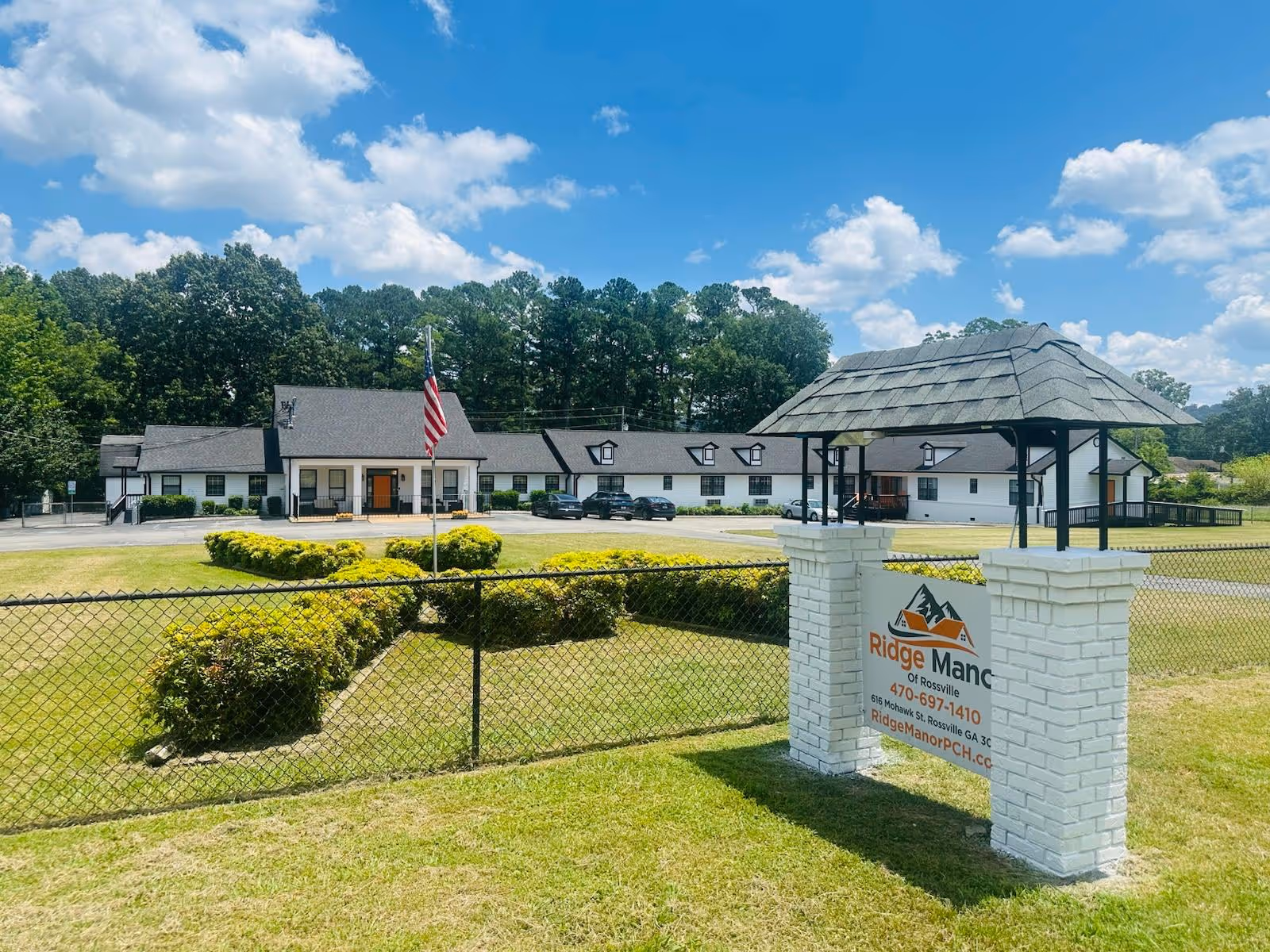 Exterior view of Ridge Manor of Rossville with a white building, sign, and flag.