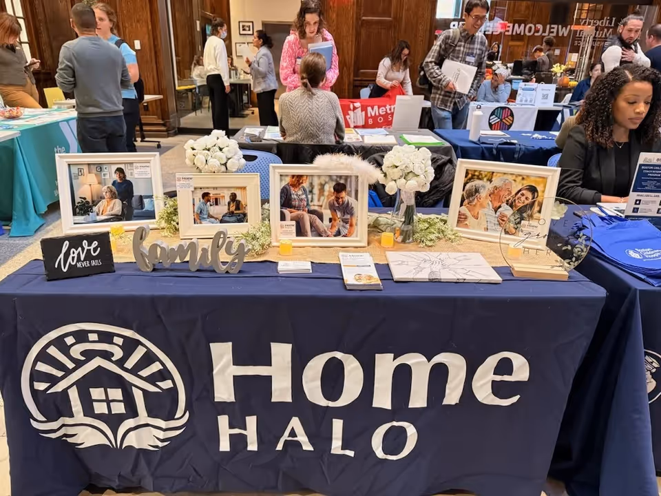 Indoor expo booth for Home Halo of Plano with framed photos and attendees.