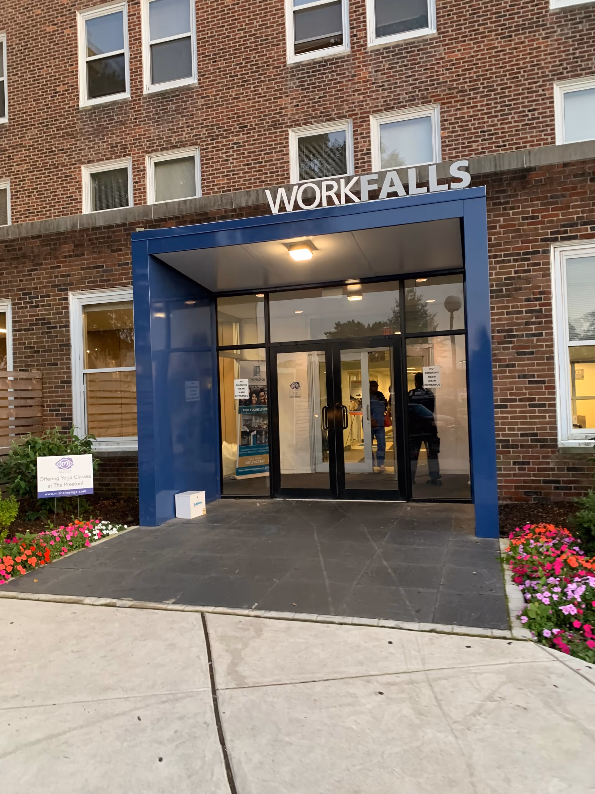 Brick building exterior with a blue-framed entrance and glass doors.