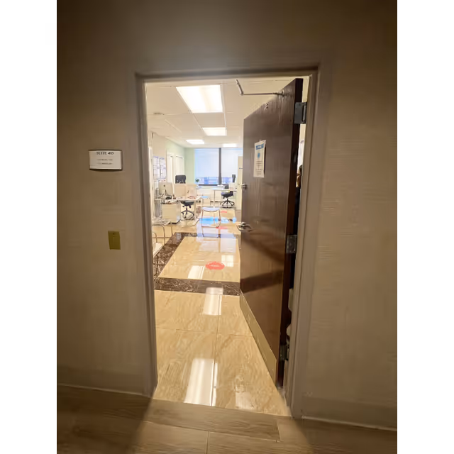 Open door reveals a bright office area with desks, chairs, and computers.